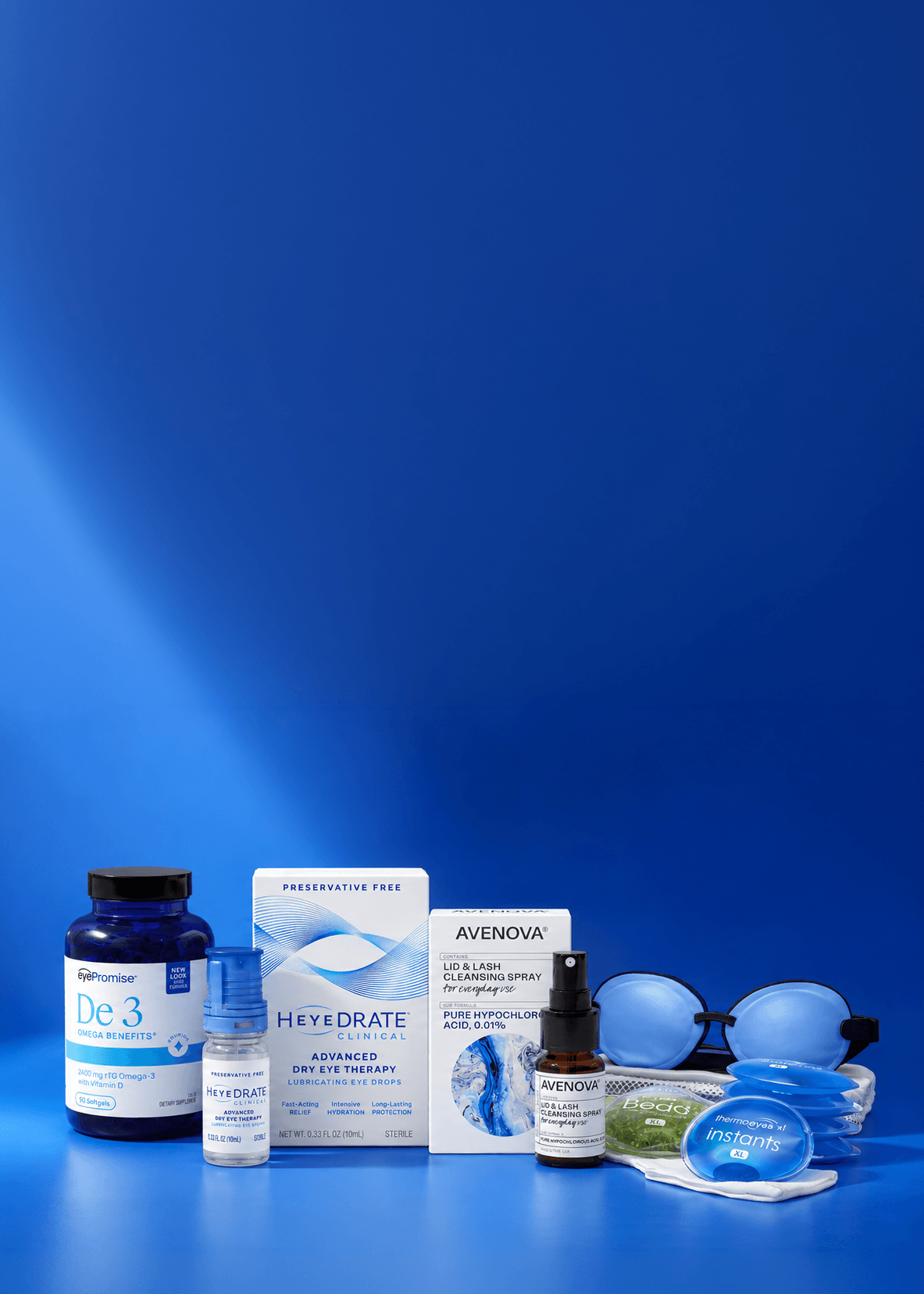 A group of eye care products arranged on a blue studio background, including a large blue bottle labeled De3, a small blue bottle, a Heyedrate box, an Avenova box, a small amber dropper bottle, blue eye shields, and instant heat packs.