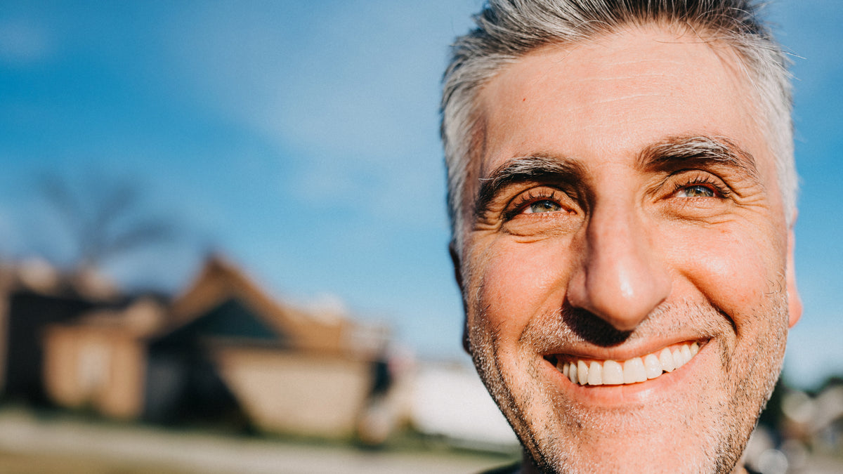 Close-up of a man with a bright smile against a blue sky